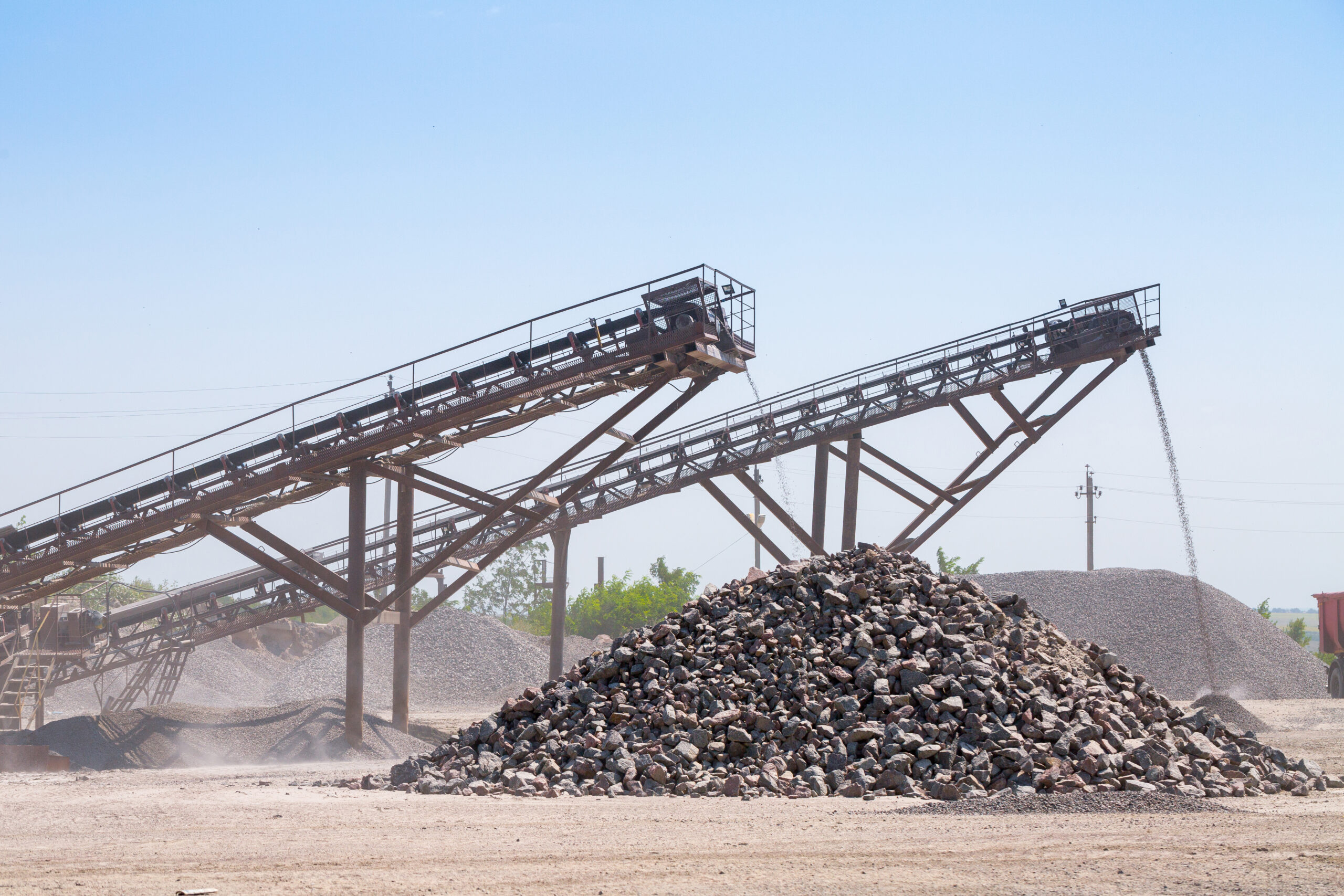 Crushing machinery, cone type rock crusher, conveying crushed granite gravel stone in a quarry open pit mining. Processing plant for crushed stone and gravel. Mining and Quarry mining equipment.